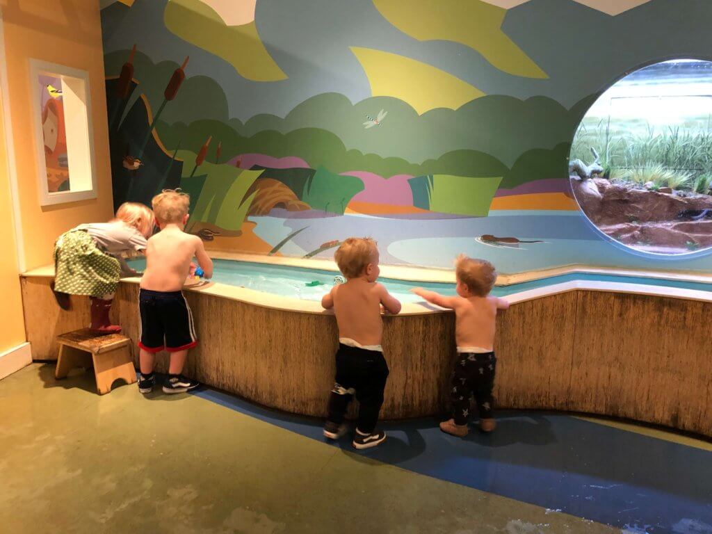 Kids playing in the water with shirts off at a Museum.